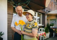 elderly couple holding bouquet of flowers while holding hands