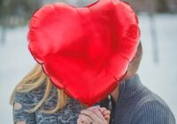 couple holding hands with red heart balloon