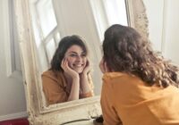 photo of woman looking at the mirror