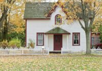 white and red wooden house with fence