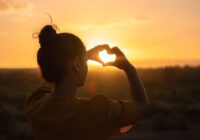 woman sitting while showing heart sign hands