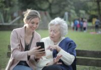 cheerful senior mother and adult daughter using smartphone together